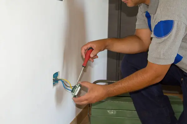 Image of a handyman electrician repairing and installing a home electrical outlet. DIY works power plug.