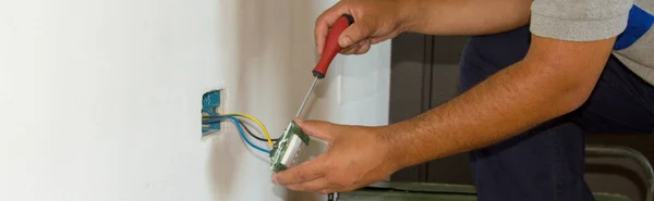 Image of a handyman electrician repairing and installing a home electrical outlet. DIY works power plug. Horizontal banner
