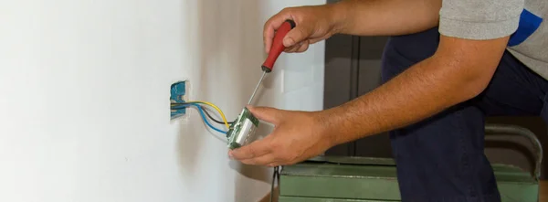Image of a handyman electrician repairing and installing a home electrical outlet. DIY works power plug. Horizontal banner