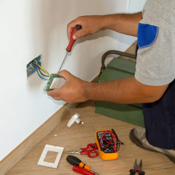 Image of a handyman electrician repairing and installing a home electrical outlet. DIY works power plug.