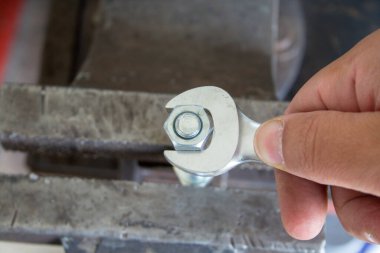 İngiliz anahtarıyla sürgüyü sıkan bir tamircinin eli. DIY atölyede çalışıyor.