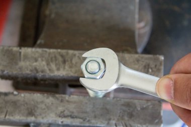 İngiliz anahtarıyla sürgüyü sıkan bir tamircinin eli. DIY atölyede çalışıyor.
