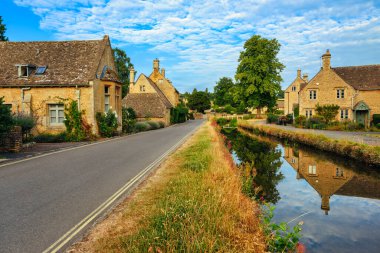 İngiltere, Cotswolds 'taki Aşağı Katliam Köyü' nde bir yaz gününde nehre yansıyan geleneksel taş evler. Aşağı Katliam Köyü Cotswold 'da en çok ziyaret edilen yerlerden biri..