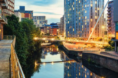 River Irwell banks in Manchester City Centre, England, illuminated in the evening clipart