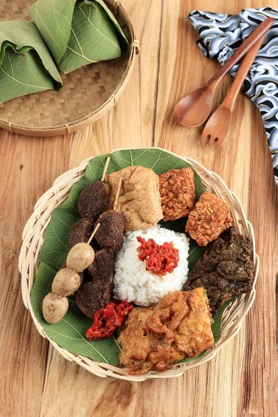 ナシJamblangまたはセガJamblang Cirebonミックス米のチークの葉で包まれた 様々なサイドディッシュを提供します 木製テーブルの上からの眺め — ストック写真