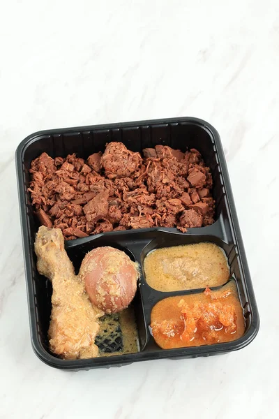 Gudeg Komplit with Chicken Opor and Egg, Served on Plastic Packaging. Concept Food on the Go. Gudeg is Traditional Indonesian Food from Yogyakarta