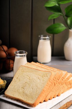 Tahta Arkaplanda Kahvaltı için Dilimlenmiş Tost Ekmeği (Shokupan veya Roti Tawar), Yumurta ve Sütle servis edilir. Fırın Kavram ResmiComment