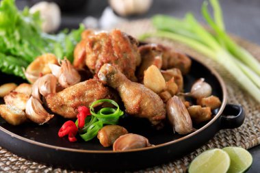 Chicken Garlic or Ayam Goreng Bawang Khas Batam, Indonesia. Fried Chicken with Garlic Special Seasoned from Chinese Influence. Served on Black Plate with Leetuce
