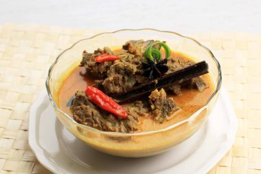 Selected Focus Gulai Sapi is Beef Curry Typically Traditional Food from Padang, West Sumatera, Indonesia. Served at the Table with Bowl and Ketupat Lebaran. Menu for Eid al Adha (Idul Adha). 