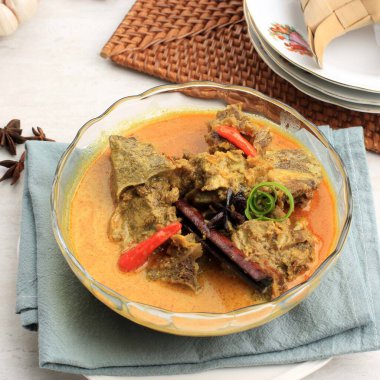 Gulai Sapi is Beef Curry Typically Traditional Food from Padang, West Sumatera, Indonesia. Served at the Table with Bowl and Ketupat Lebaran. Menu for Eid al Adha (Idul Adha)