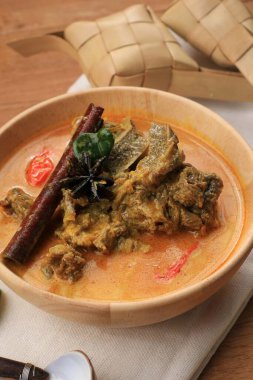 Selected Focus Gulai Sapi is Beef Curry Typically Traditional Food from Padang, West Sumatera, Indonesia. Served at the Table with Bowl and Ketupat Lebaran. Menu for Eid al Adha (Idul Adha). Served with ketupat