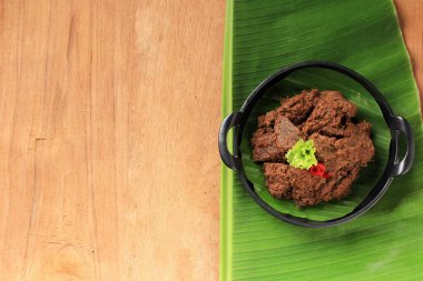 Rendang or Randang is The Most Delicious Food in the World. Made from Bees Stew and Coconut Milk with Various Herbs and SPice. Typically food from Minang Tribe, West Sumatera, Indonesia. Copy Space on Wooden Background