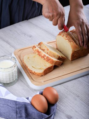 Female Home Chef Hand Cut Slicing Homemade White Japanese Brioche Loaf Bread on Wooden Board Using Knife