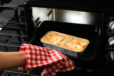 Woman Hands Taking Baking Tray with Lasagna Out of Oven