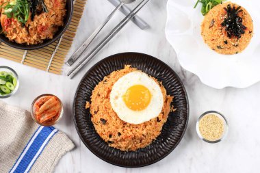 Korean Food: Bokkeumbap or Kimchi Fried Rice, South Korea Traditional Recipe Fried Rice with Kimchi, Spring Onion, Sesame Seed, Tomato, and Nori (Laver). Served on WHite Ceramic Plate