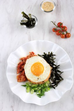 Homemade Kimchi Fried Rice Topped with Fried Egg and Seaweed on White Plate Marble Table, Overhead View. COpy Space for Text