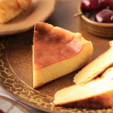 Basque Burnt Cheese Cake on Brown Plate, SLiced with Cherry on the Background 