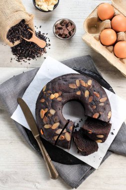 Top View Bolu Ketan Hitam, Black Sticky Rice Brownies  Cake is Indonesian Traditional Cake, Made from Black Sticky Rice Flour. Topped with Almond Slices on Black Slate Plate and White Background