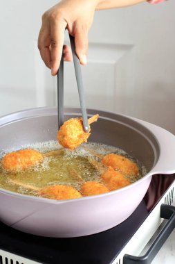 Cooking Process: Asian Female Hand Hold Kitchen Tongs, Take Out Chicken Sempol from Hot Oil, Deep Fried Sempol Ayam, Traditional Indonesian Street Food