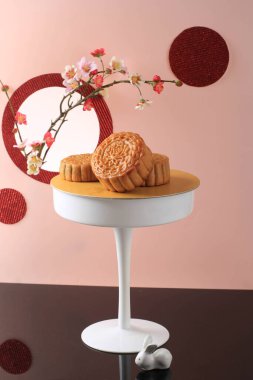 Mooncake on Light Pink Background with Pink Flower. Concept Moon Cake on Mid Autumn Festival. Mooncake Popular as Kue Bulan.