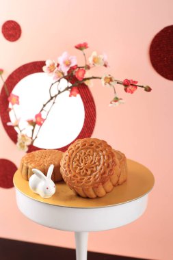 Mooncake on Light Pink Background with Pink Flower. Concept Moon Cake on Mid Autumn Festival. Mooncake Popular as Kue Bulan.