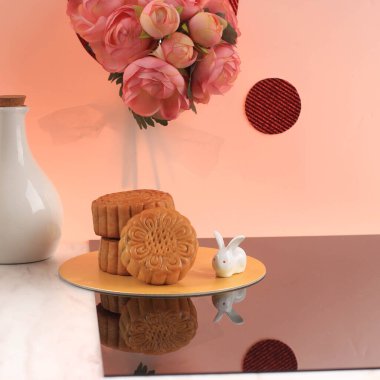 Mooncake on Light Pink Background with Pink Flower. Concept Moon Cake on Mid Autumn Festival. Mooncake Popular as Kue Bulan.