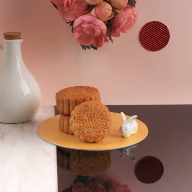 Mooncake on Light Pink Background with Pink Flower. Concept Moon Cake on Mid Autumn Festival. Mooncake Popular as Kue Bulan.