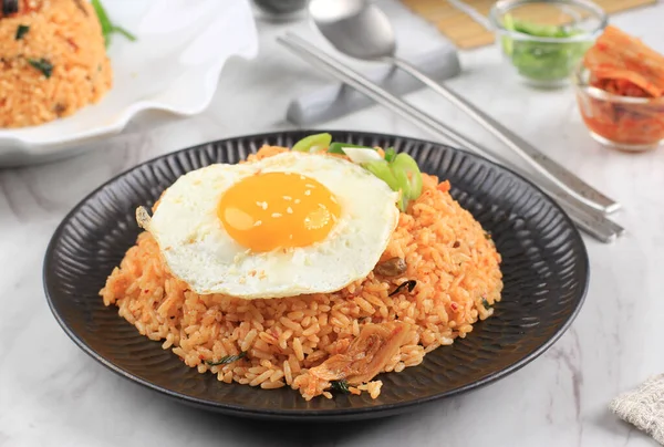 Kimchi Fried Rice with Fried Sunny Side Egg on Top. Korean Food. Served on Black Ceramic Plate