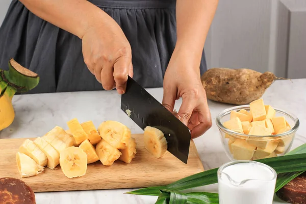 Slicing Banana, Preparation making Banana and Sweet Potato Compote (Kolak Pisang Ubi). Ripe Banana, Sweet Potato, Palm Sugar (Gula Merah), Pandan Leaves, and Coconut Milk. Popular for Ramadan Breakfasting