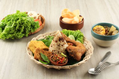 Nasi TO or Tutug Oncom. Traditional Sundanese Rice Mixed with Fermented Soybean, Accompanied with Fried Chicken, Tempeh, Tofu, Vegetables, Sambal, Sayur Asem, and Crackers.