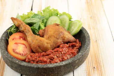 Ayam Penyet or Penyetan Ayam, Fried Chicken Served with Spicy Sambal on Wooden Table