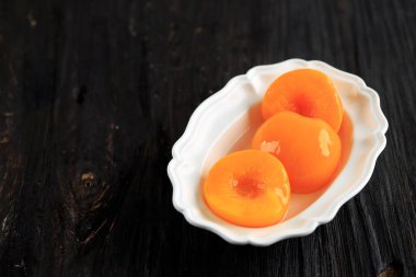 Konserve şeftali beyaz kasede tatlı şuruplu. Boşluğu Kopyala Masası Üzerinde