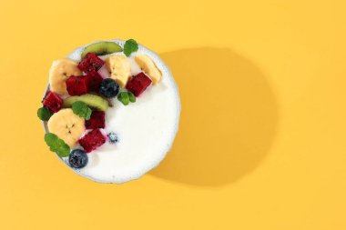 Fresh Fruit Topping ve Nane Yapraklı Yoğurt Kasesi Sarı Arkaplanda. Metin ya da Tarif için Kopyalama Alanı ile Yaz Sağlıklı Kavram 