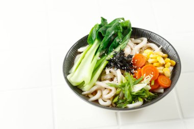 Udon Noodles, Nori ve Sebzeli Japon Vejetaryen Çorbası ve Siyah Seramik Kasesi. Beyaz Tanble 'da İzole Edilmiş 