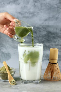 Yeşil kibriti süt ve buzlu bardağa dolduran, buzlu kirazlı yeşil çay Latte.