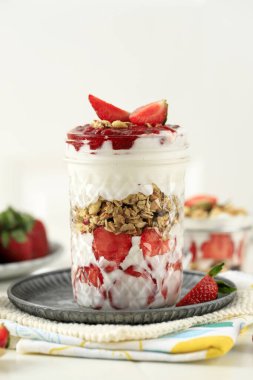 Çilekli Yunan Yoğurdu Granola Parfe Beyaz Masa 'da bir içki bardağında. Diyet Sağlıklı Gıda Konsepti 