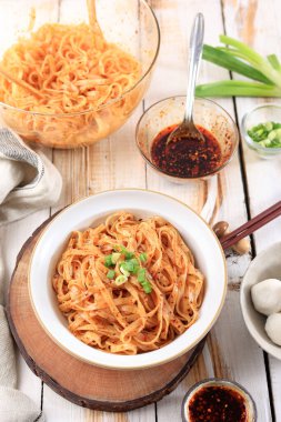 Çin pilavlı erişte, biber yağı ve taze soğanlı, genellikle balık köftesi ile servis edilir.. 