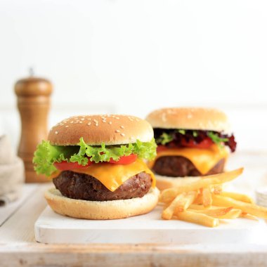 Domatesli, peynirli, marullu ve kırmızı soğanlı taze ev yapımı hamburgerin yakın çekimi..