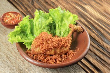 Ayam Serundeng, Indonesian Traditional Fried Chicken Recipe with Spiced Shredded Coconut. Served with Spicy Sambal. On Wooden Table 