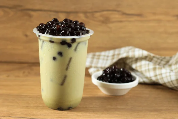 Matcha Green Tea Milk Latte with Boba Bubble Tapioca Pearl, on Wooden Table