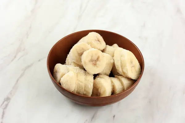 Frozen Sliced Banana on Bowl, Ingredient for Smoothies, Ice Cream, Desserts. On Marble Table