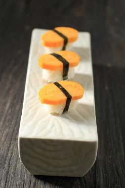 Üç Tamago Nigiri Yumurtalı Suşi Nori ile Tahta Masa, Pirinç ve Nori Kuşağı ile Yuvarlanmış Yumurta 