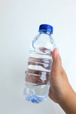 Beyaz arka planda mavi kepi mühürlü bir şişe mineral suyu tutan kadınlar. 