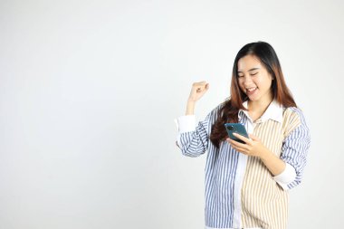 Genç Kadın Heyecanı Beyaz Arkaplanda Zafer Hareketi ve Tutucu Cep Telefonu, 