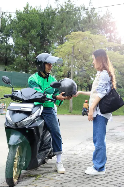 Happy Commercial Motorbike Taxi Driver Ojek Online Giving Helmet to Female Customer