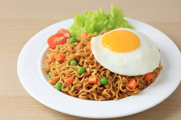 Fried Noodle Indomie Goreng with Sunny Side Egg. Popular Indonesian Instant Noodles