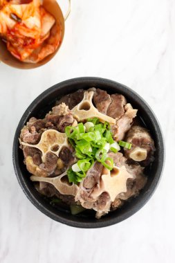 Kore Oxtail Çorbası veya Kkori Gomtang, Napa Cabbage Kimchi ile servis edilir. 