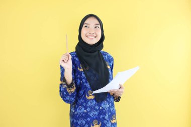 Korpti Batik Üniformalı Genç ASN Hükümet İşçisi Kalem tutuyor, Belge Kağıtlarını Kontrol Ediyor