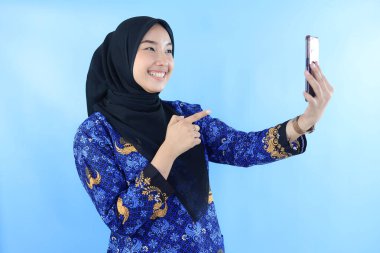 Indonesian Young ASN Woman Video Call using Mobile Phone, Wearing Blue Batik Korpri Uniform  clipart