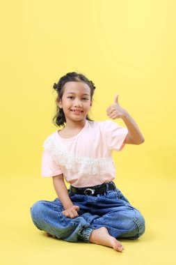 Asian Çocukları Oturur ve Başparmağını kaldırır 